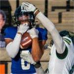 GVSU football player makes a catch while a defender tries to knock the ball away.